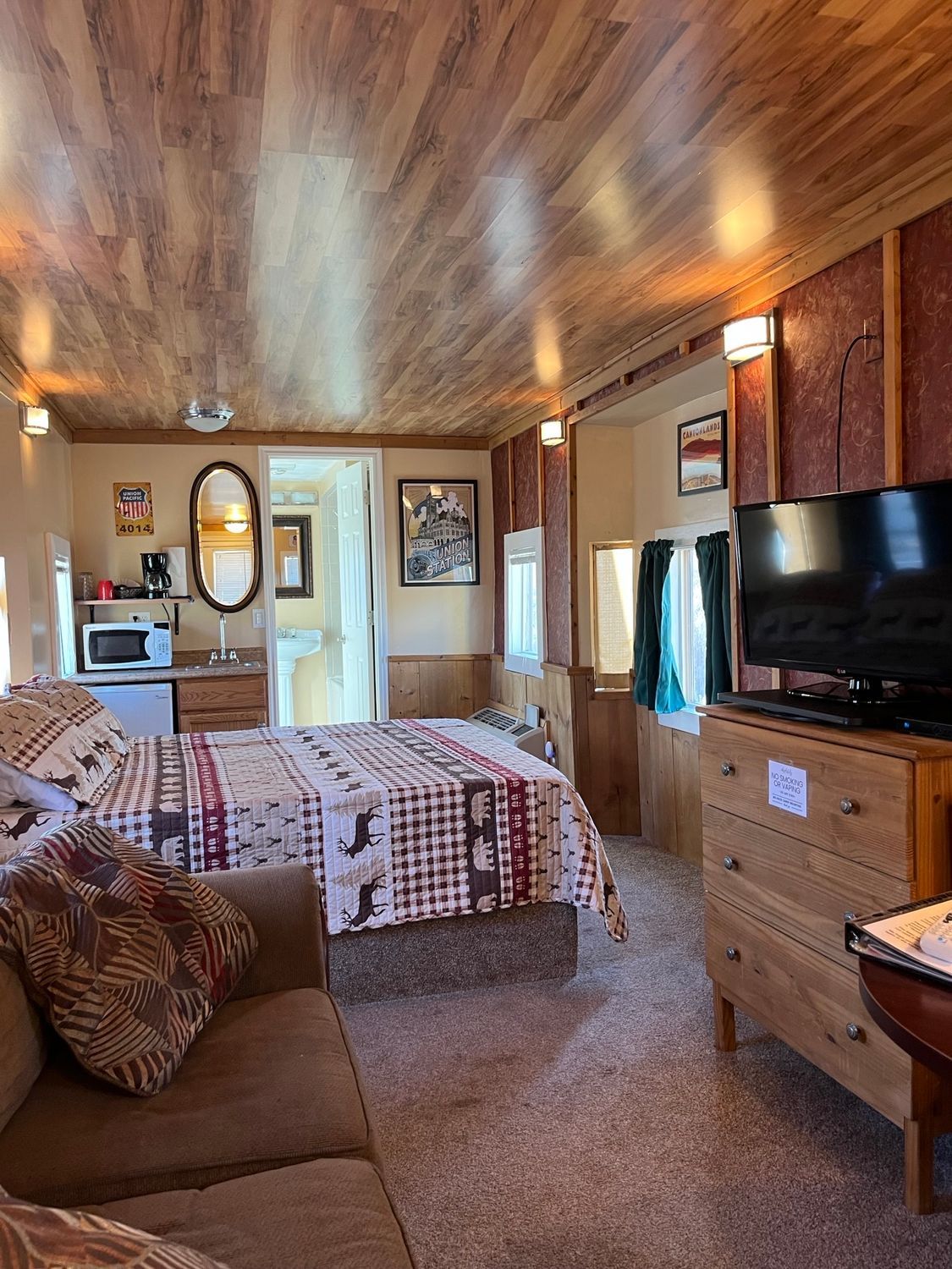 A room with a bed , couch , television and dresser.