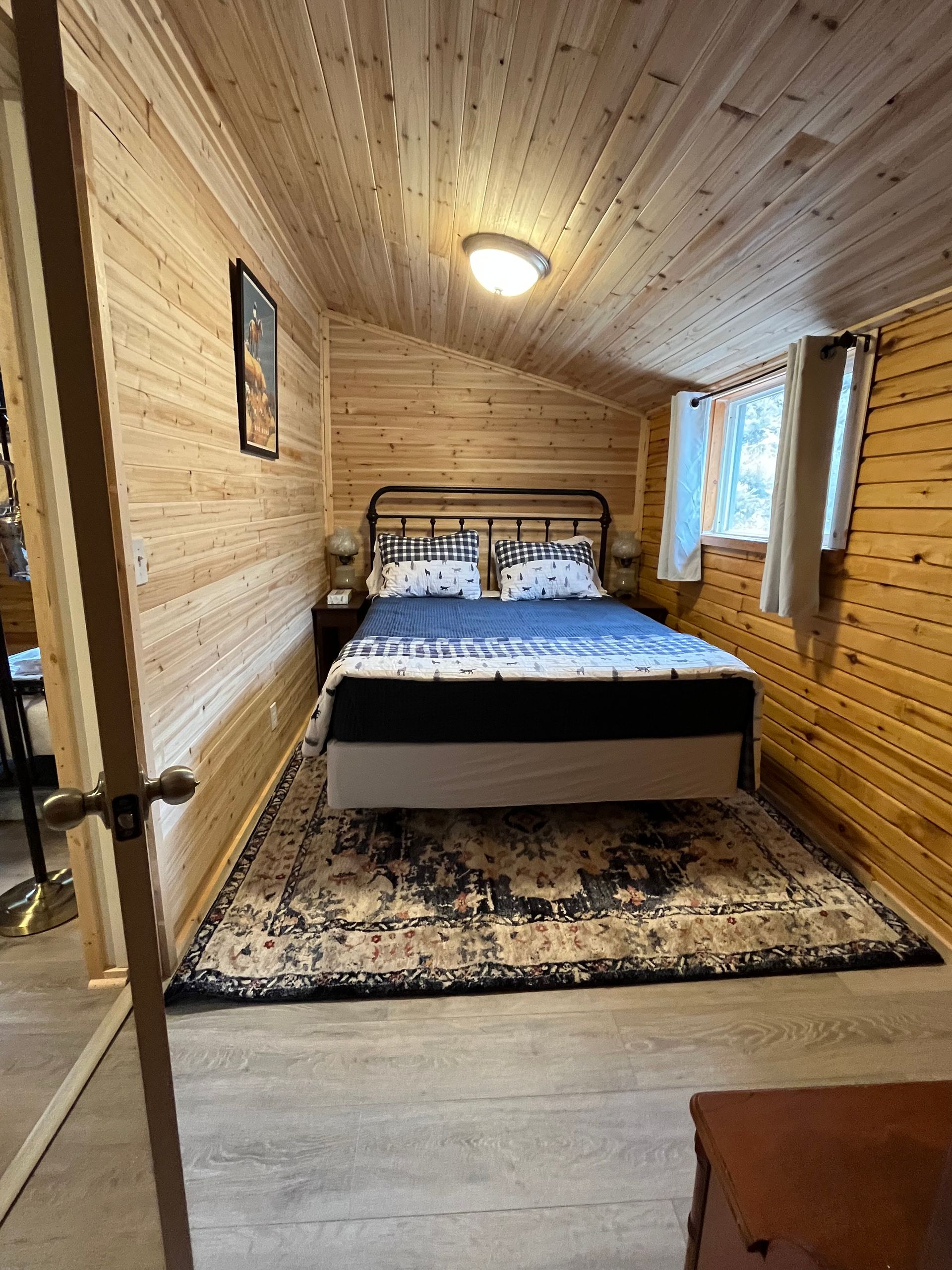 A bedroom with a bed and a rug in a cabin.