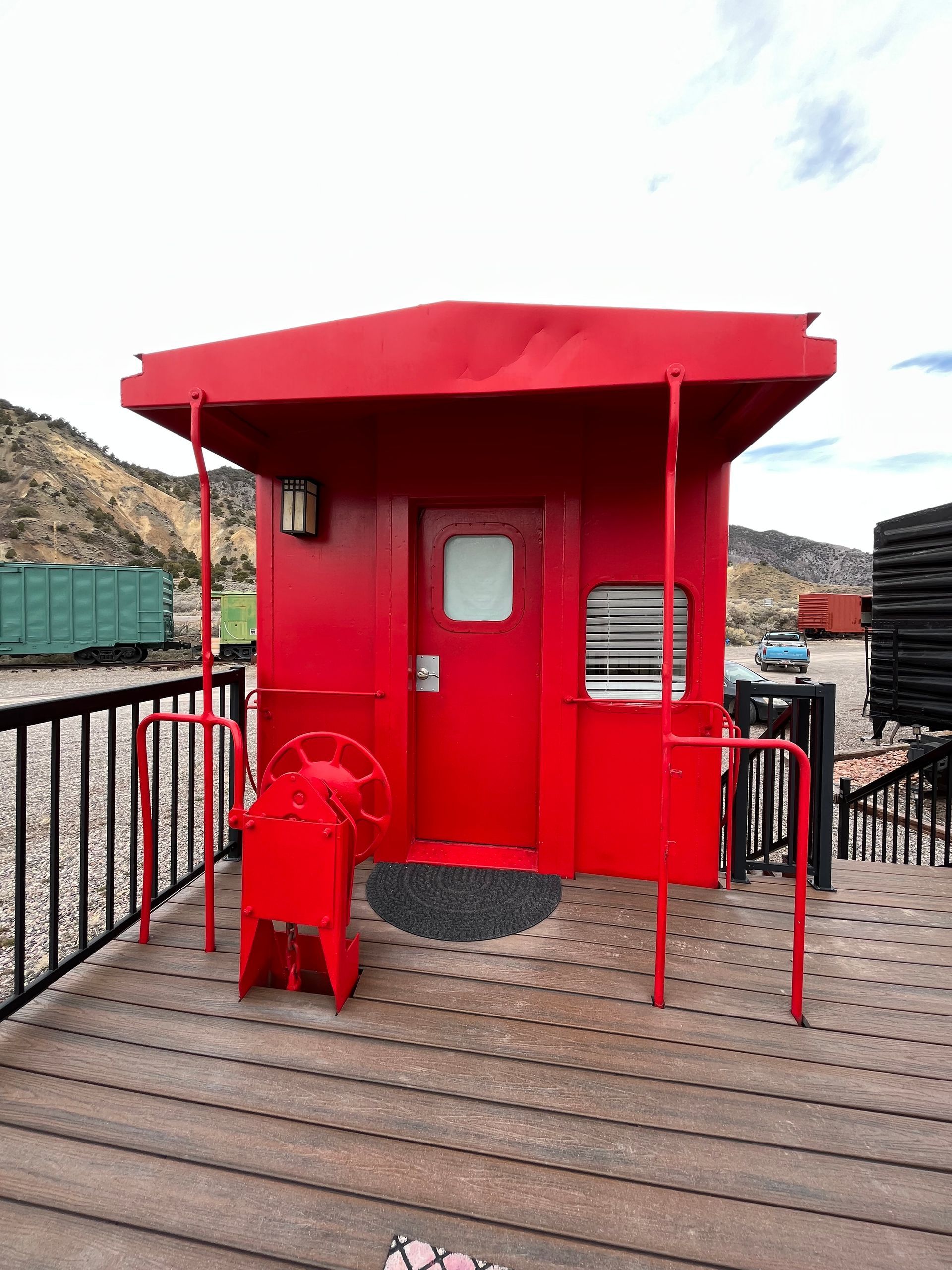 A red building with a red roof is on a wooden deck.