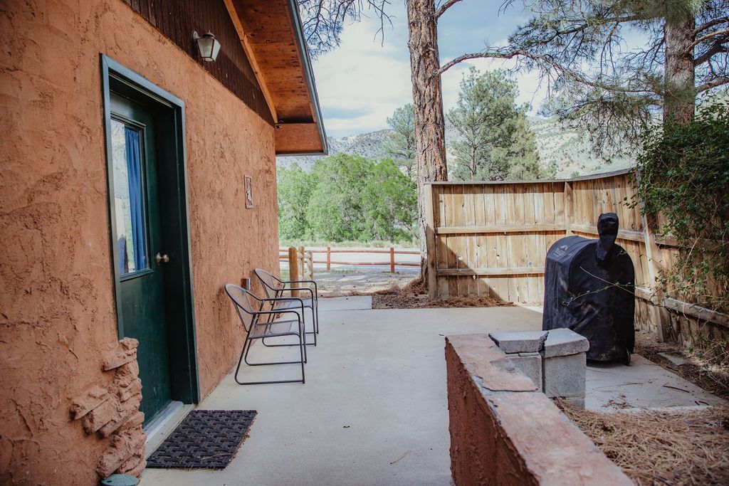 A patio with a grill and chairs in front of a house.
