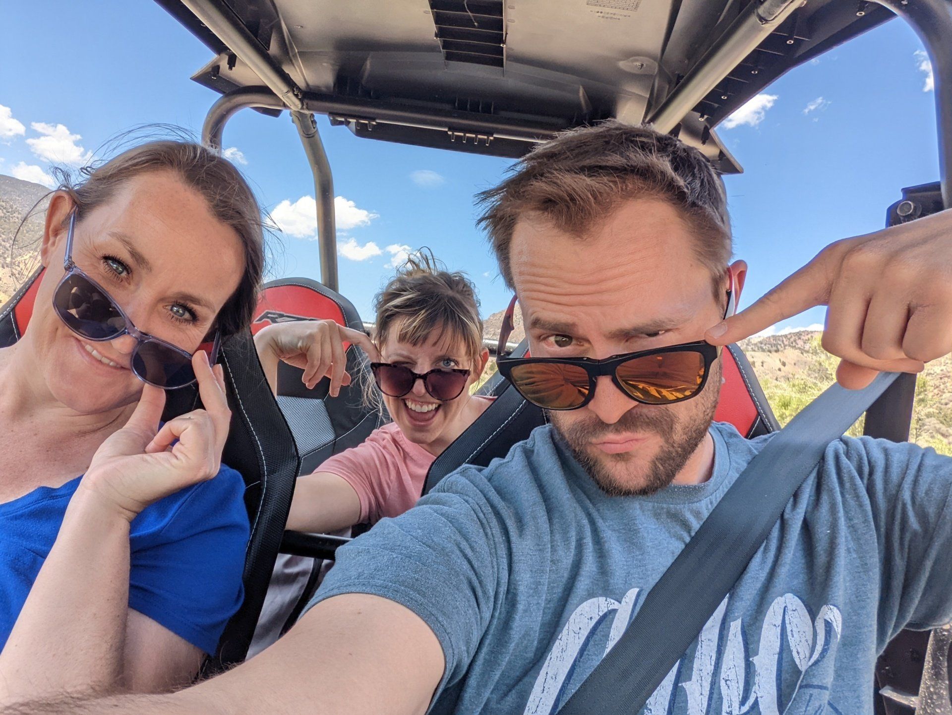 A man and two women are sitting in a buggy.