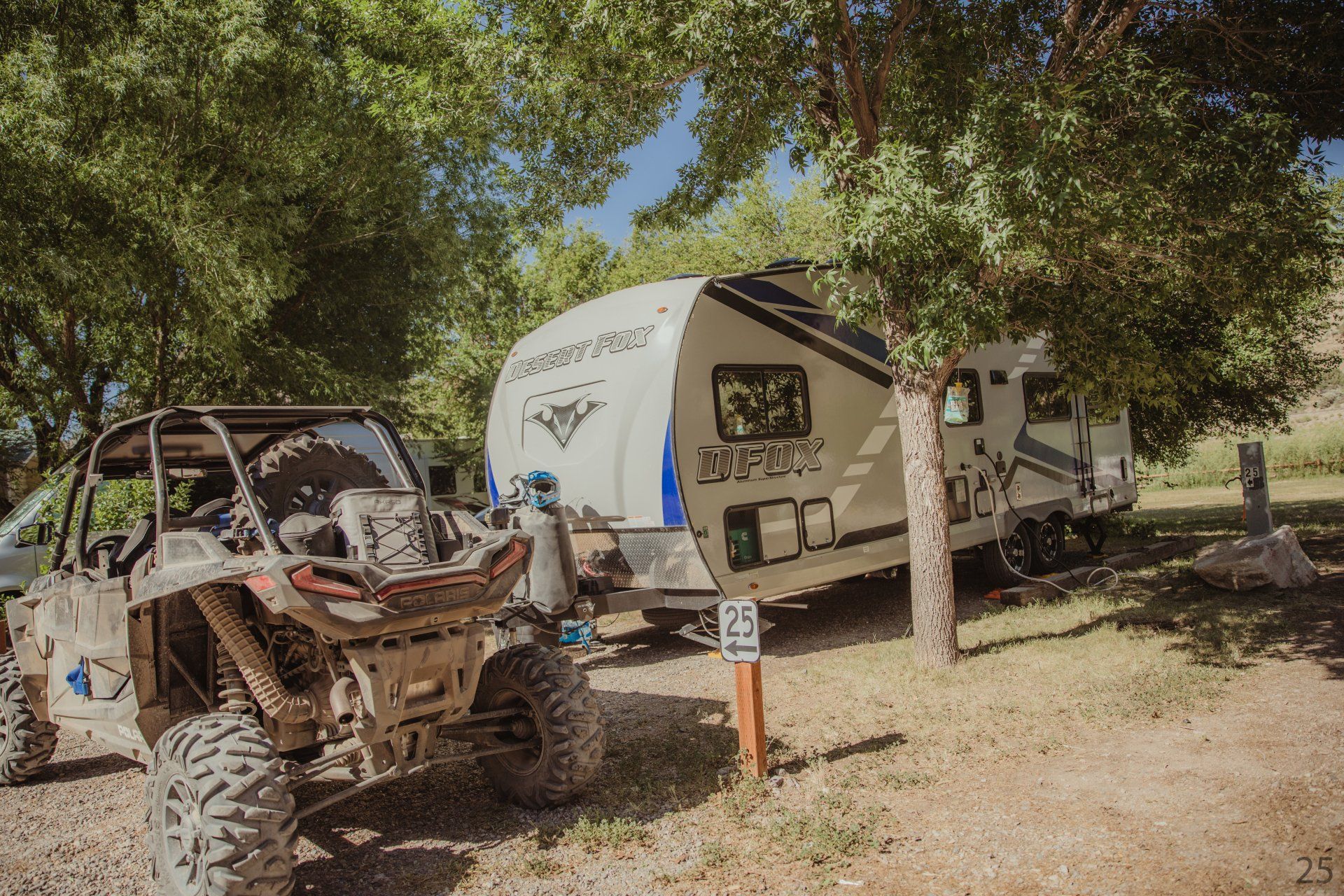 A atv is parked next to a trailer at a campground.