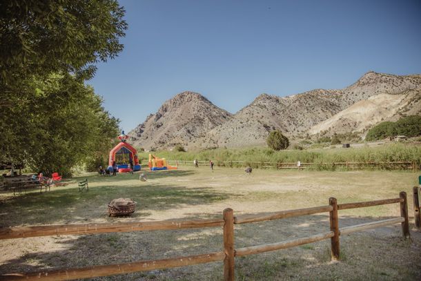 There is a bouncy house in the middle of a field with mountains in the background.