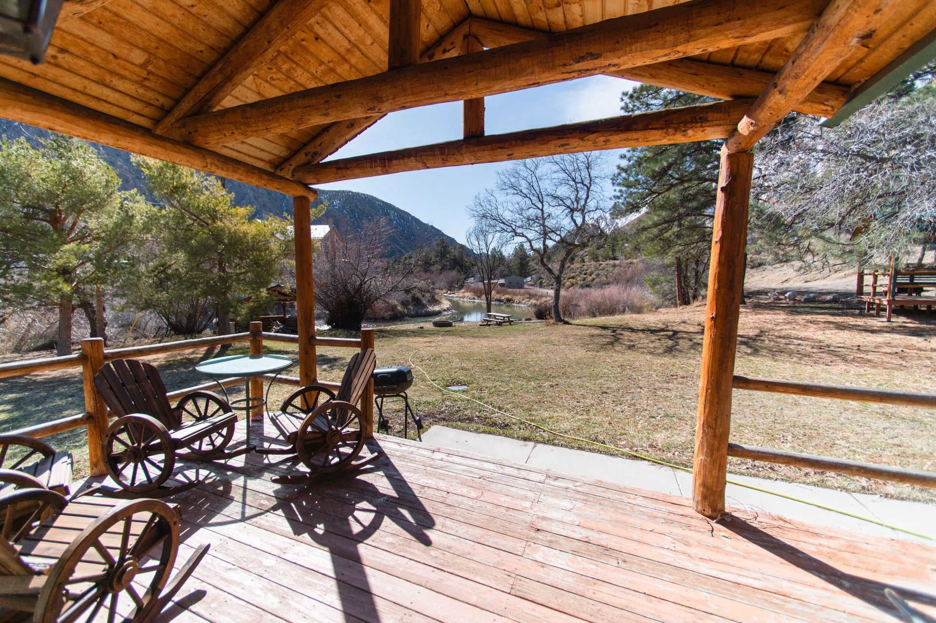 A wooden porch with rocking chairs and a table.