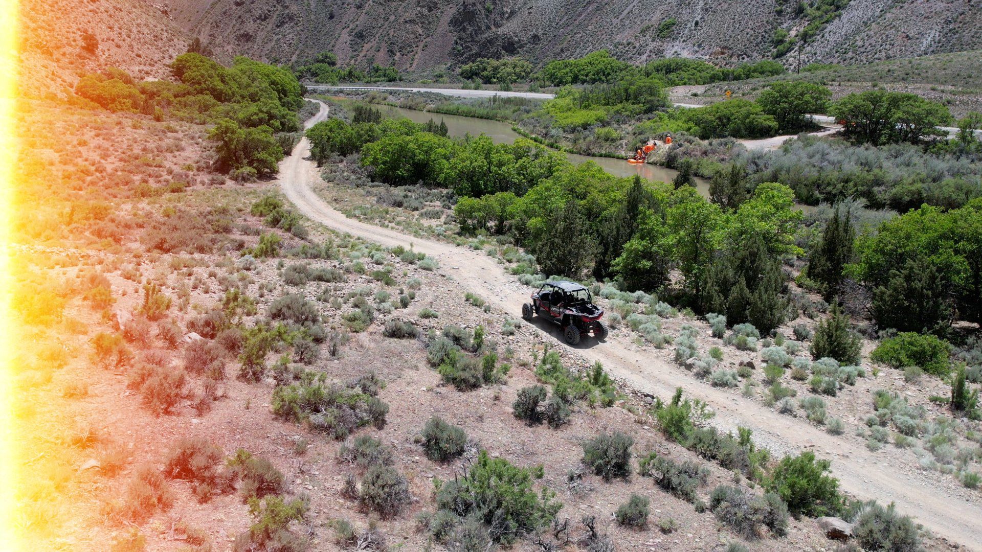 An aerial view of a jeep driving down a dirt road.