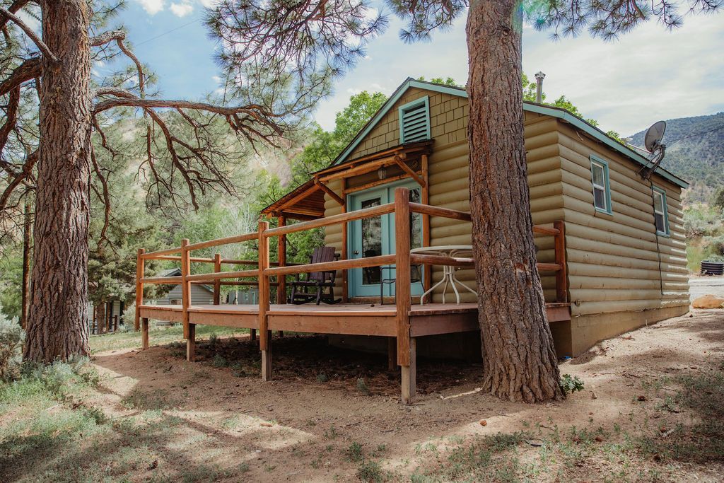 A small log cabin with a deck surrounded by trees.