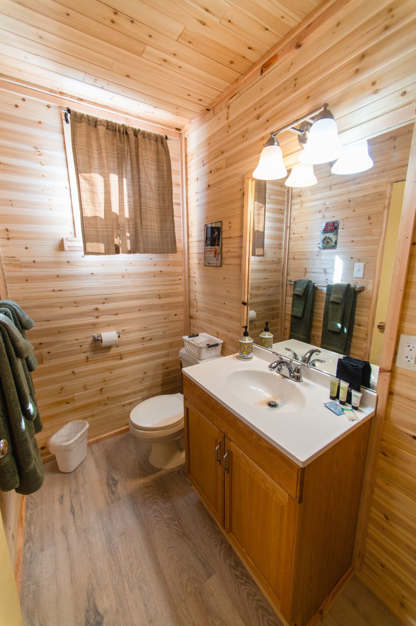 A bathroom with a sink , toilet , mirror and window.