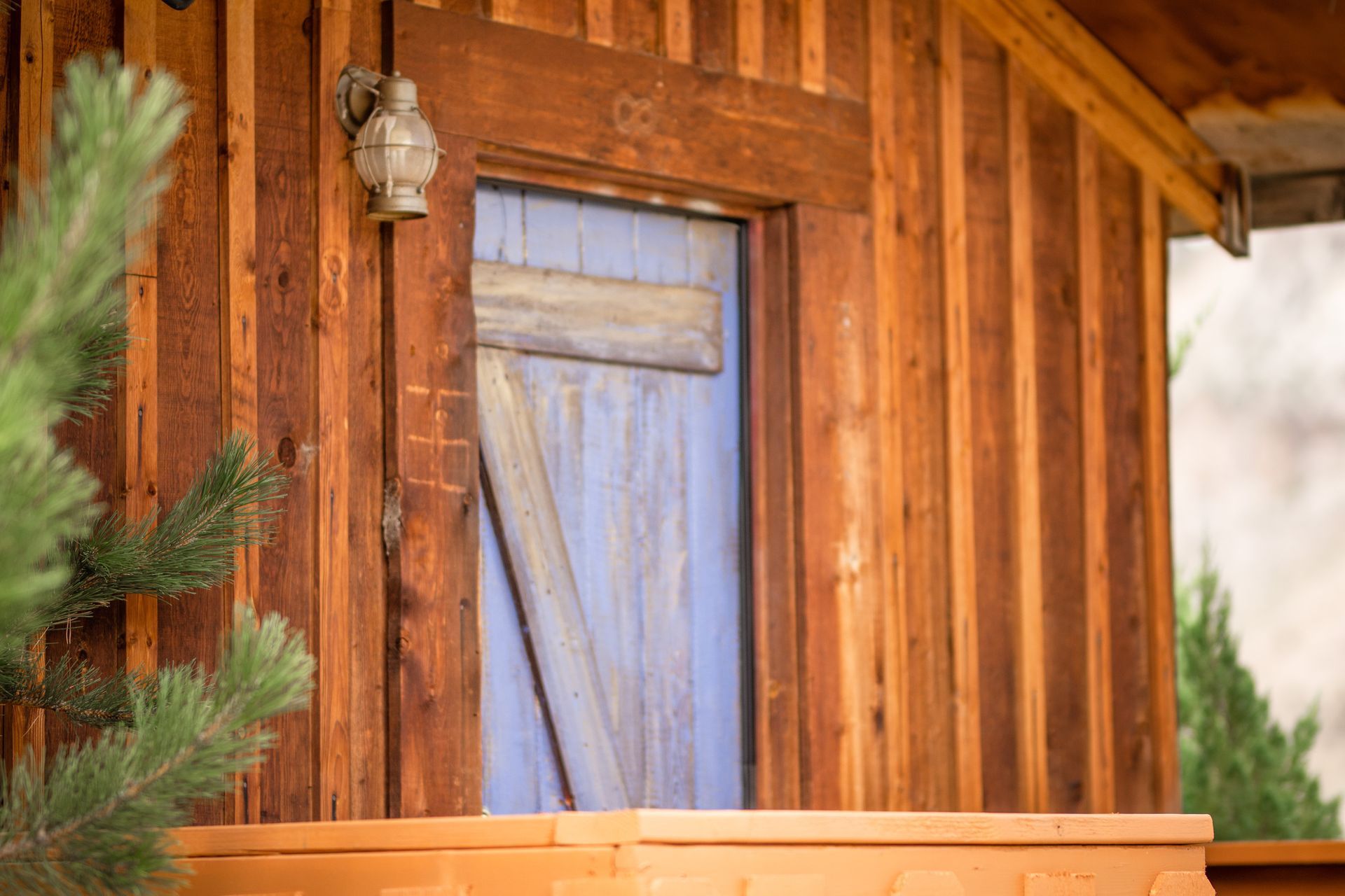 A wooden building with a blue door and a light on the side.