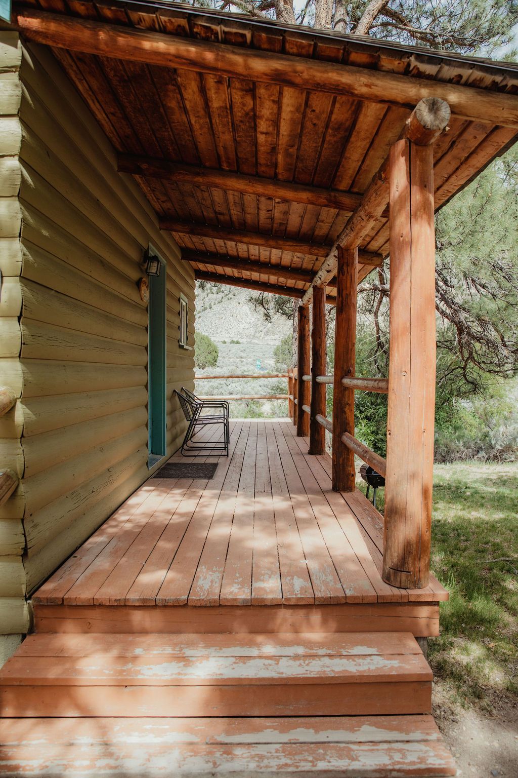 A log cabin with a wooden porch and stairs leading to it.