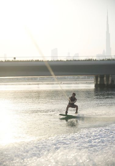 wakeboarding on calm water with a city skyline in the background