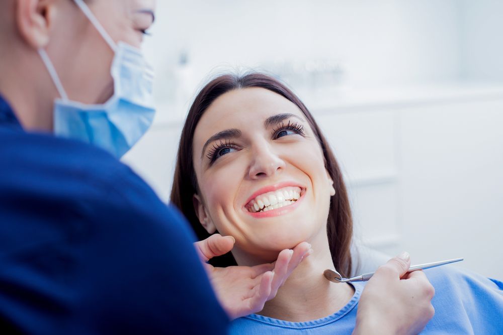 A Dentist and Assistant Wearing Medical Scrubs, Masks, and Gloves Perform a Procedure — Mareeba Dental Centre in Mareeba, QLD