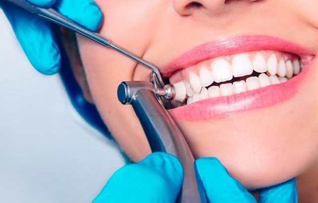 A Dentist in Blue Gloves Uses a Drill and Mirror to Examine a Patient’s Teeth — Mareeba Dental Centre in Mareeba, QLD