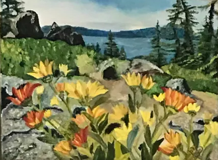 Wildflowers in a rocky meadow by a lake, with pine trees, boulders, and distant mountains under a blue sky