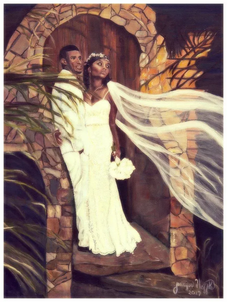 Bride in a white flowing gown with veil, standing in a stone archway with autumn leaves.