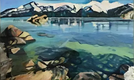 Painted mountain lake with rocky shoreline, blue-green water, and snowcapped peaks under a cloudy sky