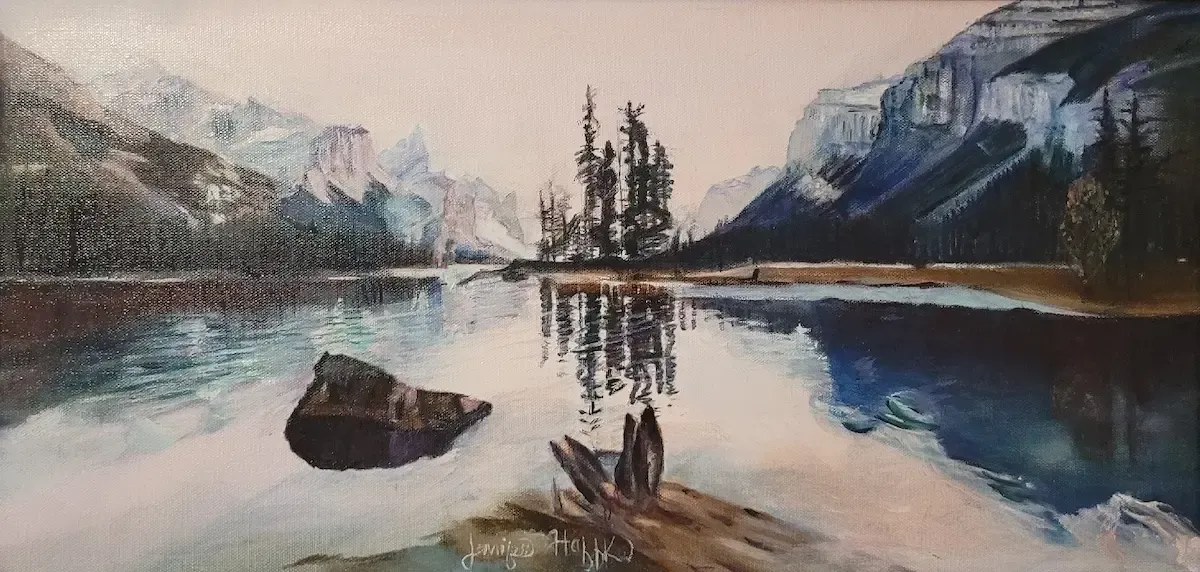 Snowy mountain lake with calm reflections, dark rocks, and trees under a soft sky