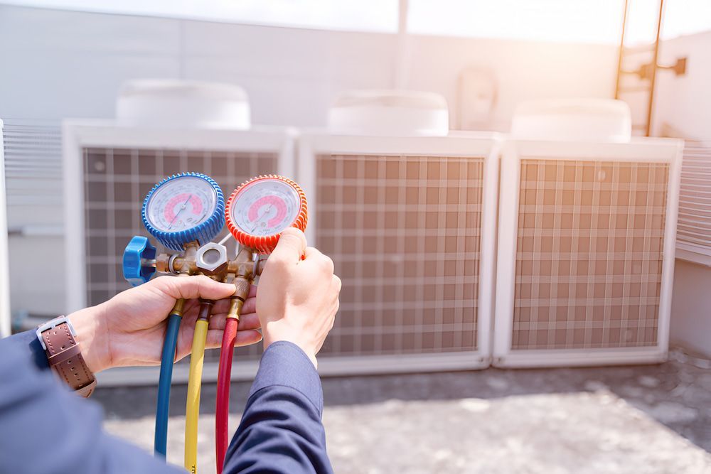 A Man Is Holding A Couple Of Gauges In His Hands — BT Airconditioning In Portsmith, QLD