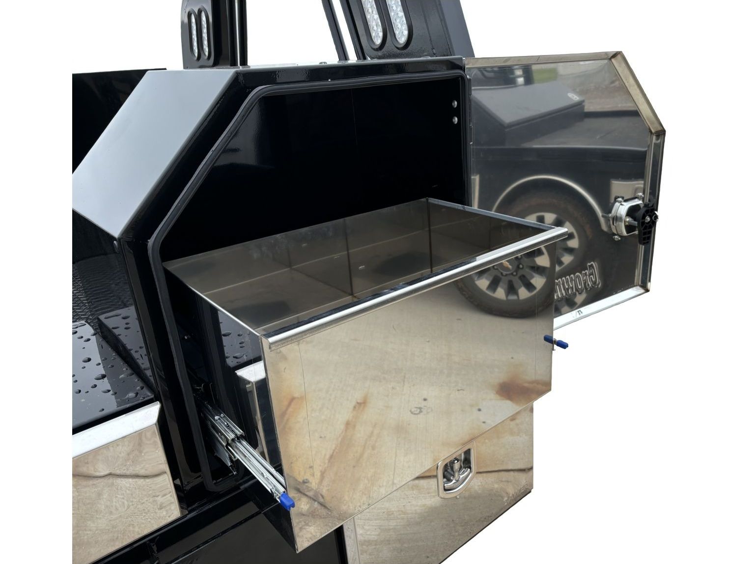 A black truck bed with a stainless steel drawer open.