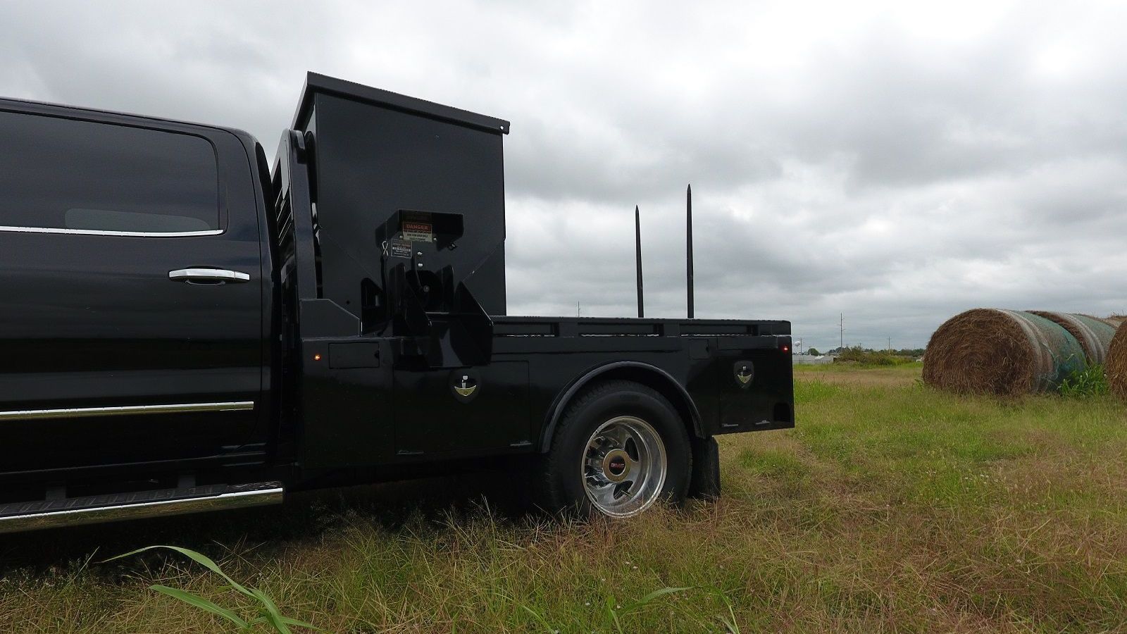 photo of cube feeder installed on truck in hay field with round bale in background