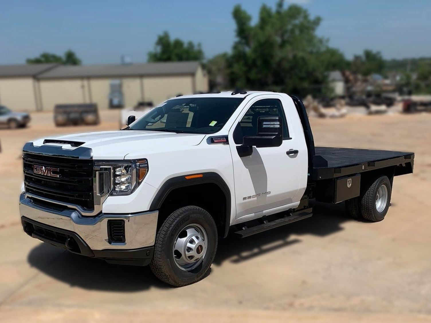 a white GMC truck with a Crownline flatbed is parked in a dirt field .