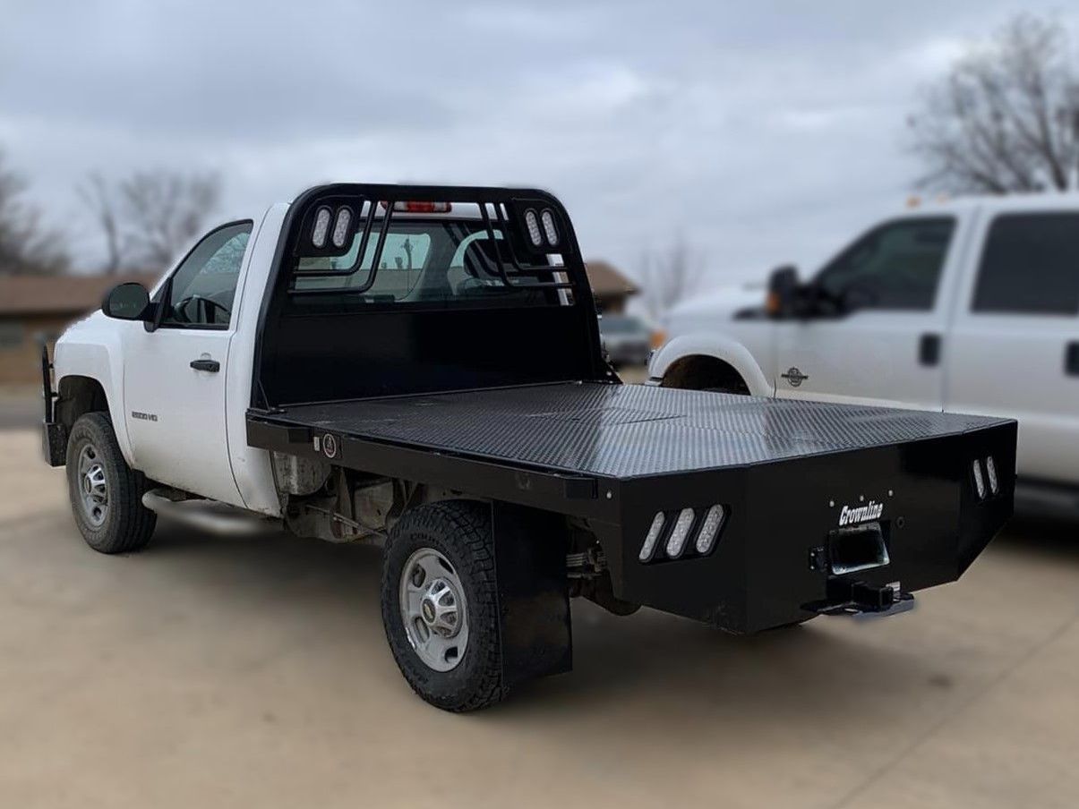 a white truck with a flat bed is parked in a parking lot .