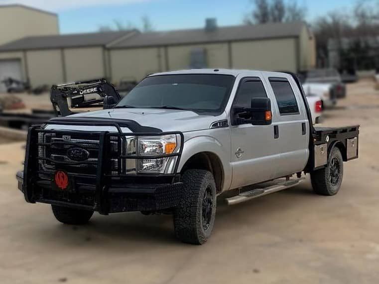 a silver truck with a flat bed is parked in a parking lot .