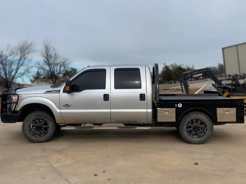 a silver truck with a flat bed is parked on the side of the road .