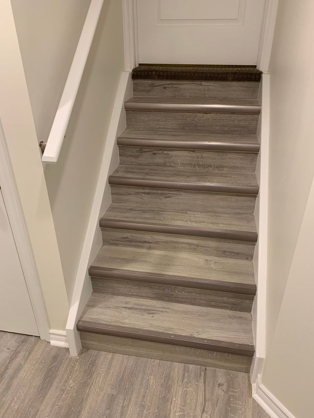 Narrow carpeted staircase in a beige hallway leading to a white door
