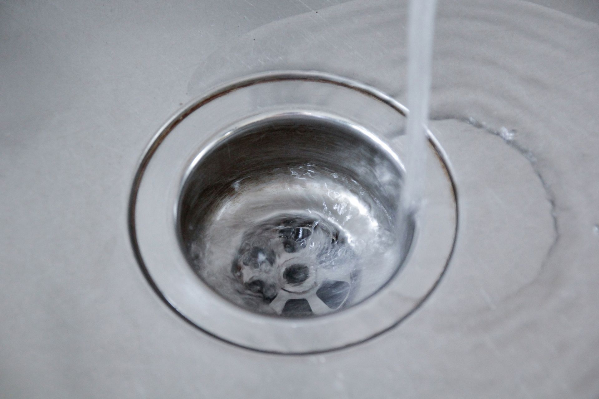 Water flowing down a silver sink drain. Water flowing down a silver sink drain.