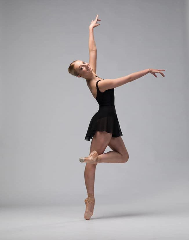 Ballet Dancer in Black Leotard, en Pointe, Arm Raised, Smiling — Kay Flynn Dancing Academy Southport in Southport, QLD