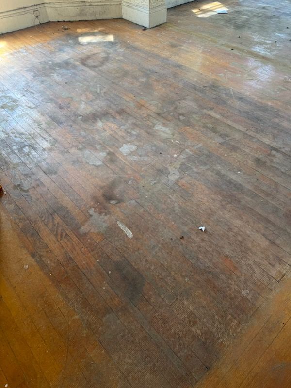 Worn wooden floor with water stains and sunlight in an empty room