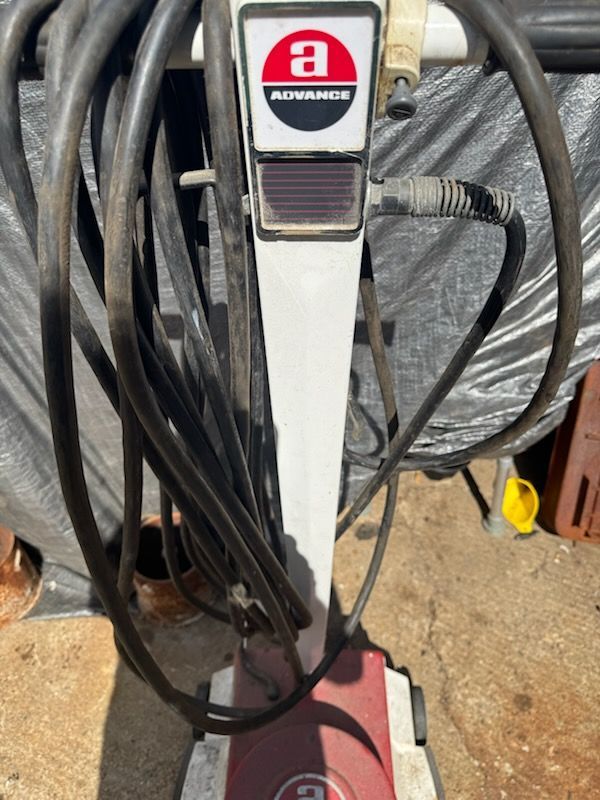 Vacuum cleaner standing among tangled cords on a concrete floor