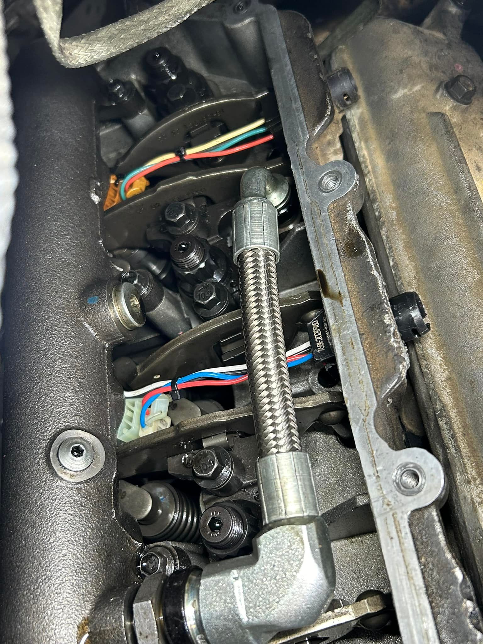 A close up of the inside of a car engine with a hose attached to it.