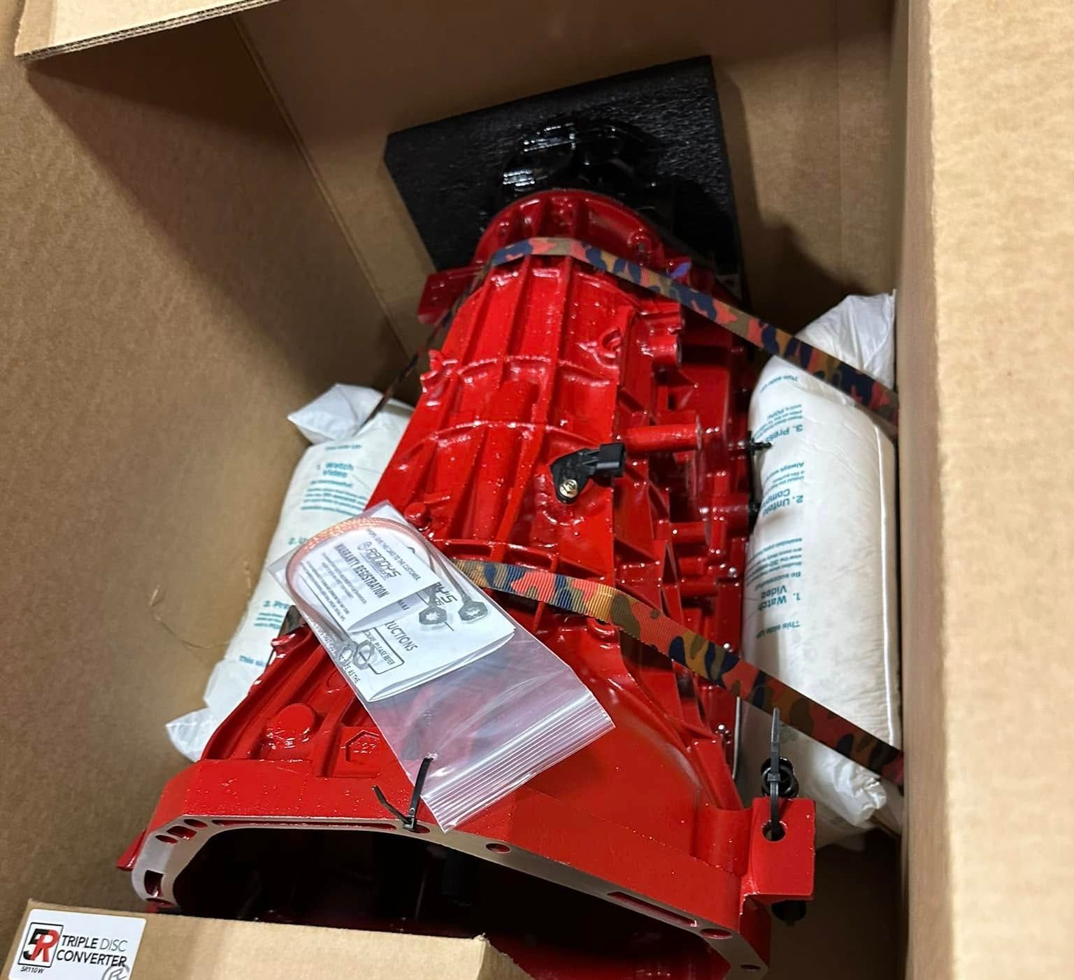 A red engine is sitting in a cardboard box