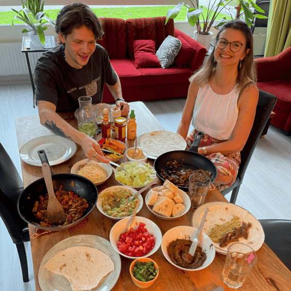 A man and a woman are sitting at a table with plates of food.