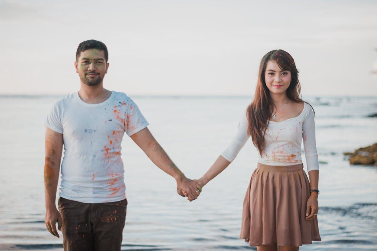 A man and a woman are holding hands on the beach.