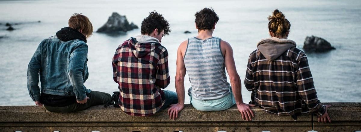 A group of people are sitting on a wall overlooking the ocean.