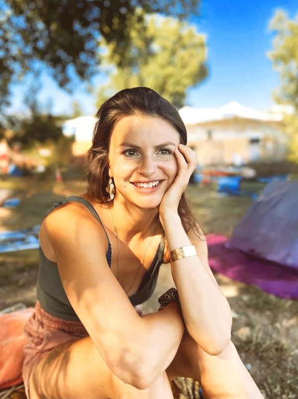 A woman is sitting in the grass with her hand on her face.