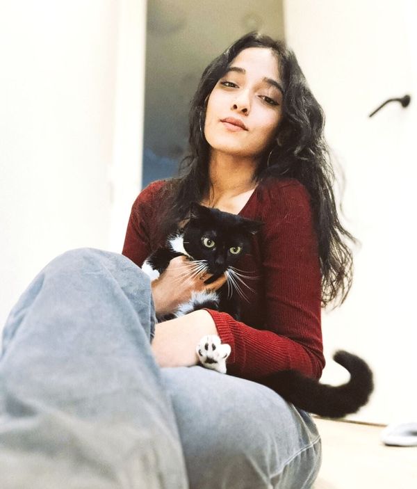 A woman in a red sweater is holding a black cat