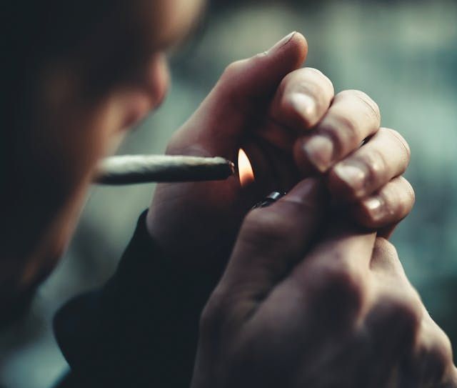 Man lighting a cannabis cigarette to numb his shame