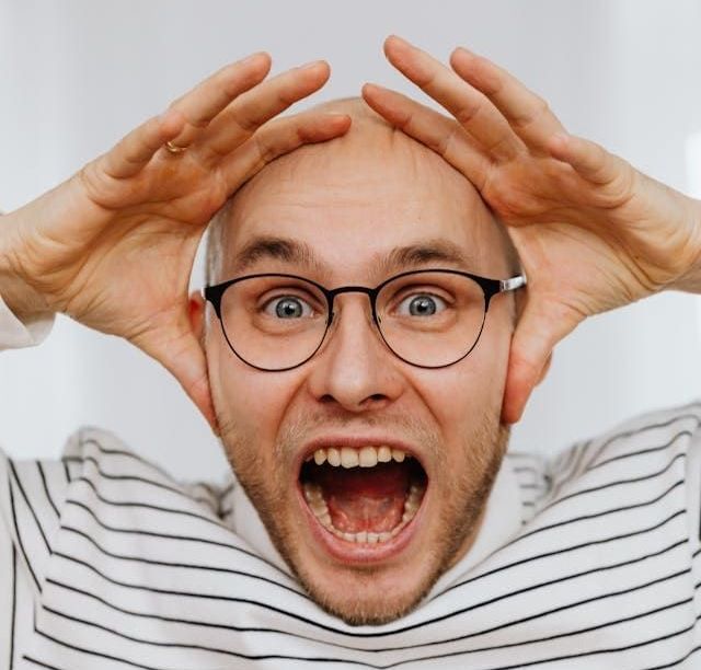A man wearing glasses is making a funny face with his mouth open