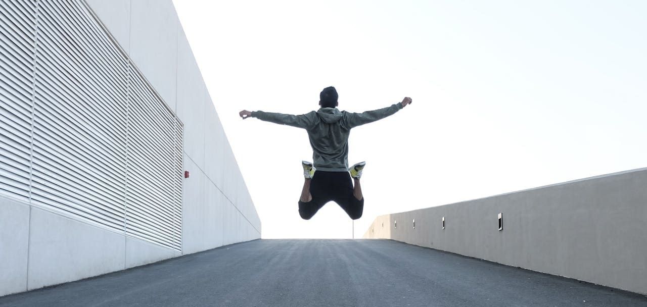 A man is jumping in the air with his arms outstretched.