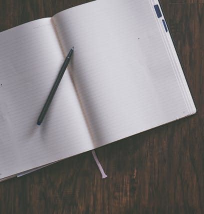 An open notebook with a pen on a wooden table