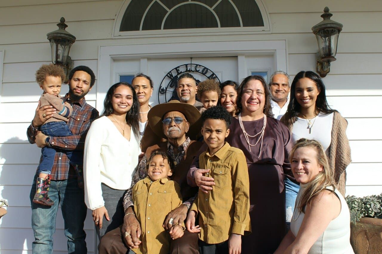 A large family is posing for a picture in front of a white building.