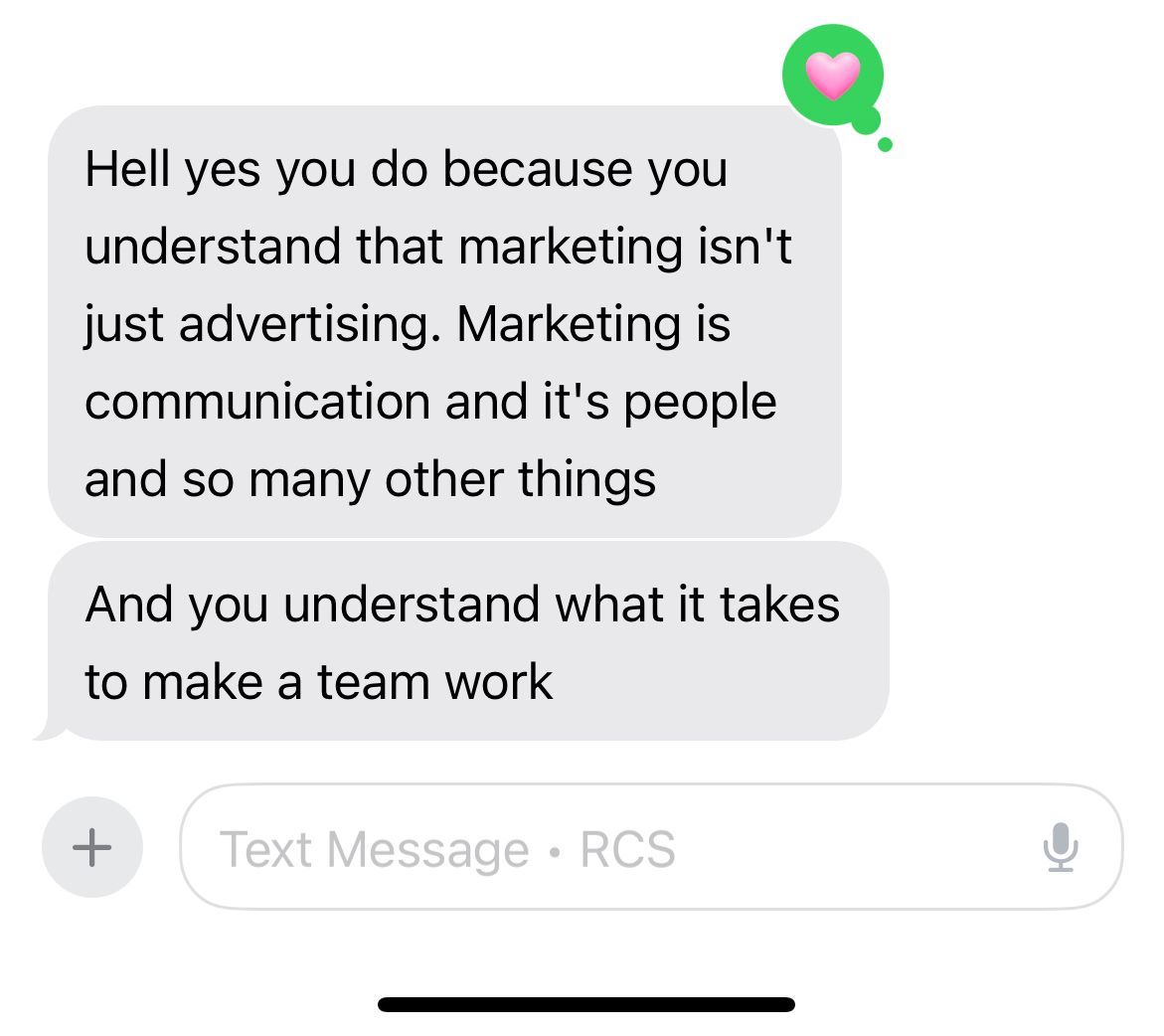 Text message screenshot showing a gray chat bubble about marketing and teamwork with a small green heart icon.