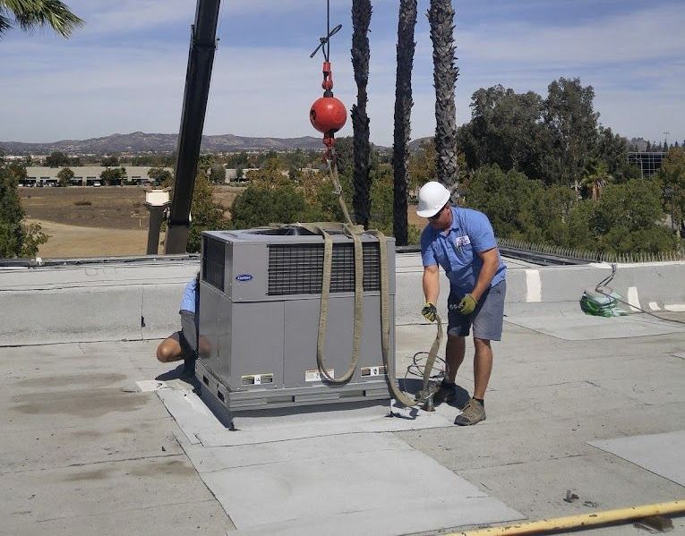 A man is working on a carrier air conditioner on a roof