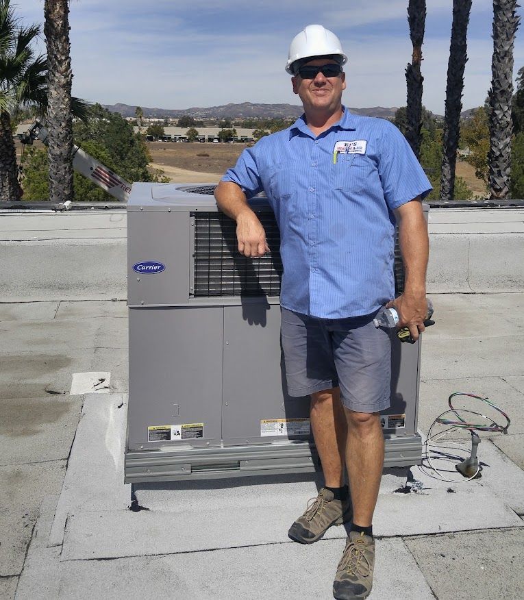 A man wearing a hard hat stands in front of a carrier air conditioner