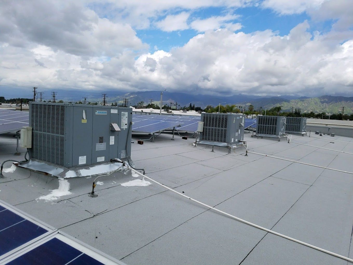 A roof with a lot of air conditioners and solar panels on it.