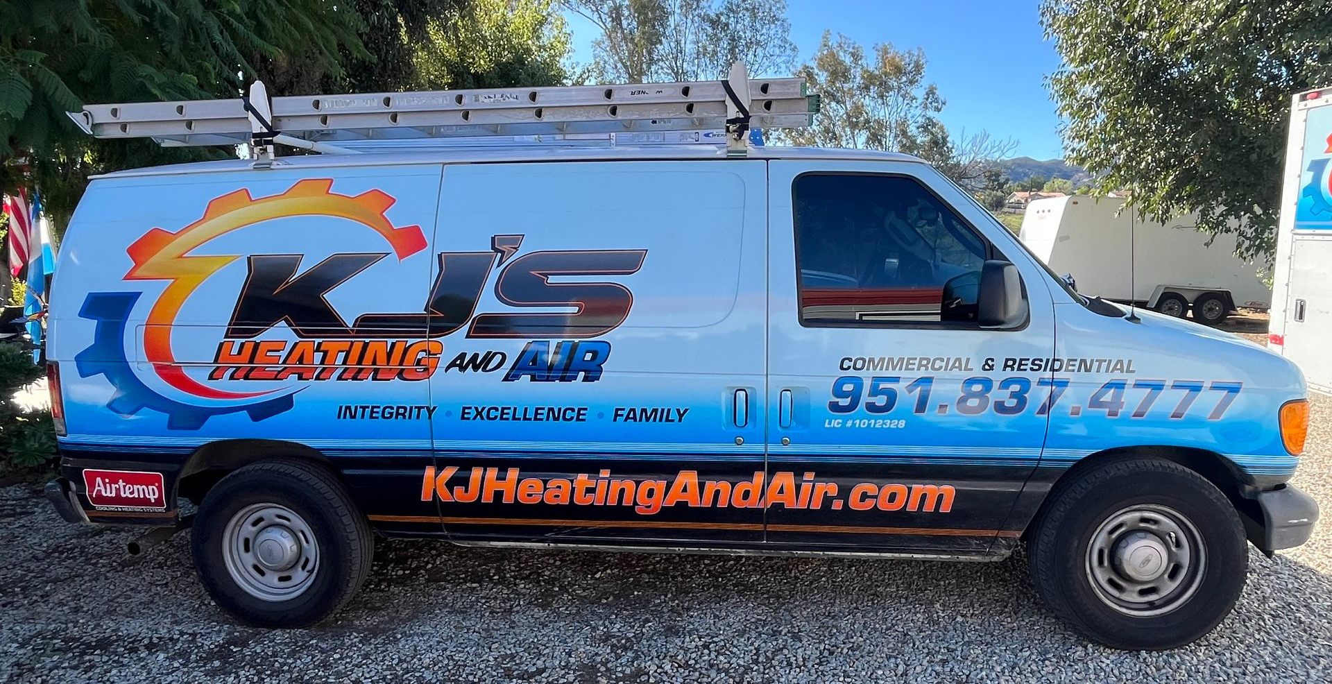 Blue KJ Heating and Air service van parked outdoors with company logo and phone number on the side