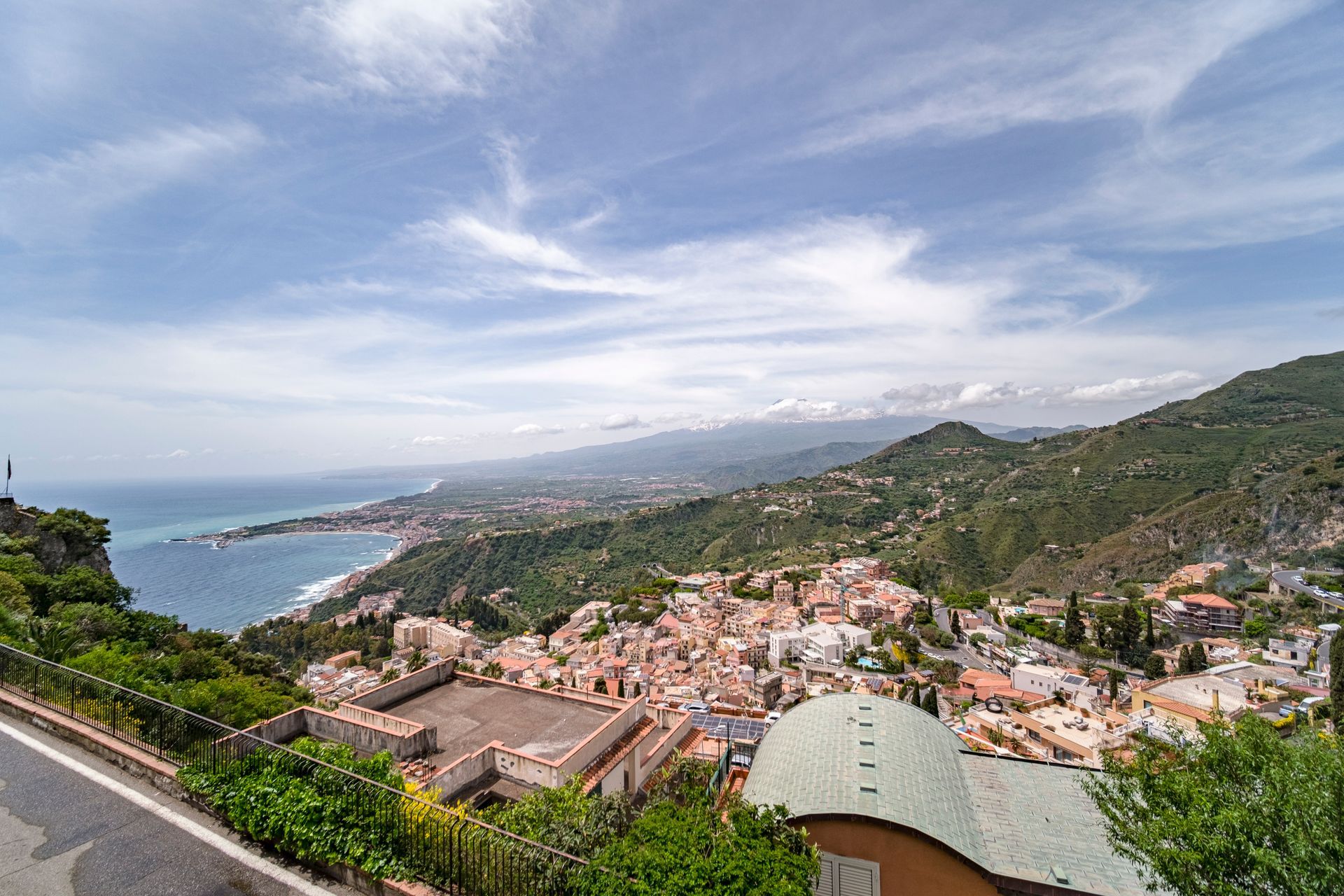 Cittadina costiera collinare con edifici dai tetti rossi e una baia sotto un cielo nuvoloso